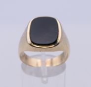 An unmarked 9 ct gold and onyx gentleman's signet ring. Ring size T. 8.8 grammes total weight.