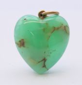 An unmarked gold mounted jade heart shaped pendant. 2.5 cm high.