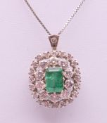 An unmarked white gold emerald and diamond pendant/brooch on a white gold chain.