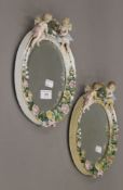 Two Continental porcelain mirrors, decorated with cherubs. Each approximately 26 cm high.