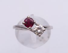 An unmarked 18 ct white gold ruby and diamond two stone crossover ring. Ring size O/P. 3.