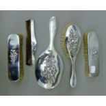 A silver dressing table set embossed with flowers. The mirror 28 cm high.