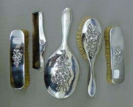 A silver dressing table set embossed with flowers. The mirror 28 cm high.