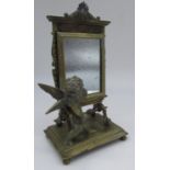 C20th French brass toilet mirror in the form of a Cherub artist before a cheval glass, on