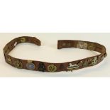 Leather army style belt mounted with various cap badges and military buttons, mostly British,