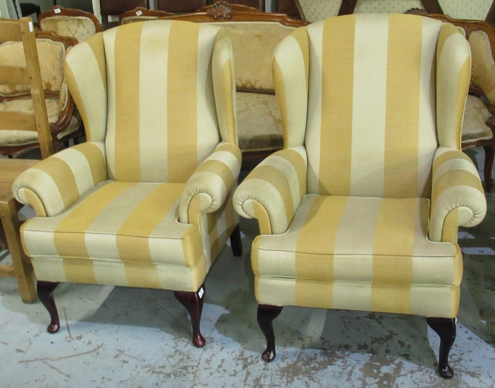 Pair of wing back armchairs, upholstered in alternating bold gold striped fabric, with loose seat