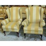 Pair of wing back armchairs, upholstered in alternating bold gold striped fabric, with loose seat