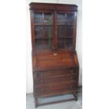 C20th oak bureau-bookcase, two glazed doors and fall front above three drawers on turned supports