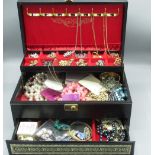Black leather cantilever jewellery box containing costume jewellery including brooches, bracelets,