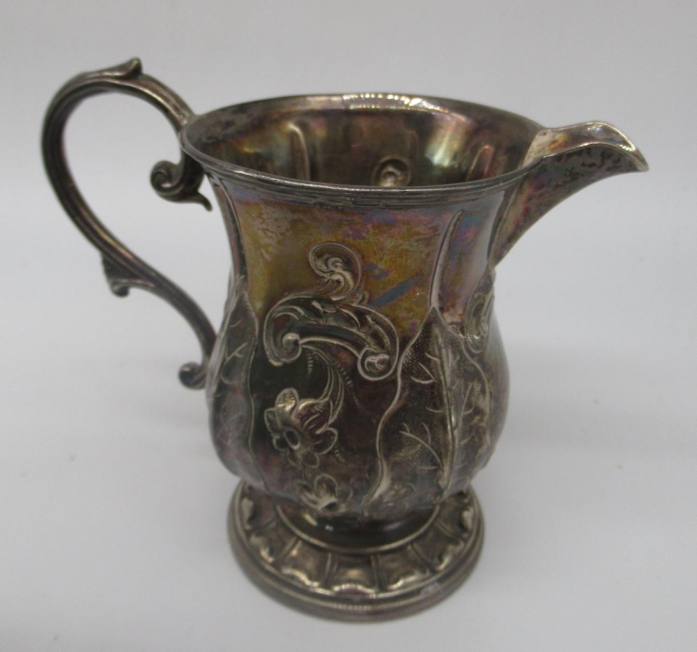 Victorian cream jug with repousse decoration and acanthus scroll handle on circular foot, makers