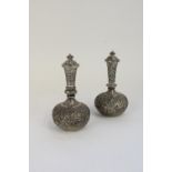 Near pair of Indian white metal covered vases, heavily embossed with dancing masked figures and