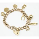 9ct yellow gold charm bracelet with heart padlock clasp and safety chain, with eight 9ct yellow gold