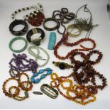 Semi precious jewellery including a carved jade bangle, an amethyst necklace, amber beads and a