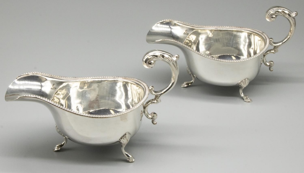 Pair of Geo.V hallmarked silver sauceboats, with gadrooned rims and S scroll handles on shell and