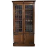 Art Nouveau oak bookcase, moulded cornice above pair of clear and coloured leaded glass doors