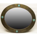 Liberty of London - a hammered brass oval mirror with nailed fold over rim, set with four Ruskin