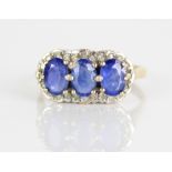 9ct yellow gold diamond and sapphire ring, set with three oval cut sapphires surrounded by a