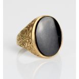9ct yellow gold signet ring, the oval face set with black stone, on scroll detailed shoulders and
