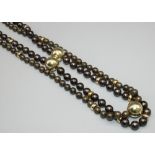 Double strand black pearl necklace, each pearl individually knotted, the 18ct yellow gold box and