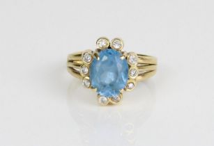 18ct yellow gold cluster ring, the central oval cut blue stone surrounded by brilliant cut diamonds,