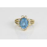 18ct yellow gold cluster ring, the central oval cut blue stone surrounded by brilliant cut diamonds,