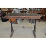 Early C20th pub table, rectangular wooden top on pierced scrolled tapering cast iron end supports