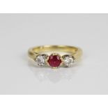 18ct yellow gold three stone ruby and diamond ring, the central round cut ruby flanked on either