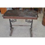 Early C20th pub table, rectangular wooden top on pierced scrolled tapering cast iron end supports