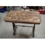 Early C20th pub table, rectangular wooden top on pierced scrolled tapering cast iron end supports