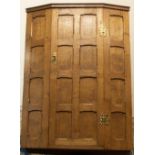 Yorkshire oak - a panelled oak corner cupboard, door with brass H handles revealing two shelves,