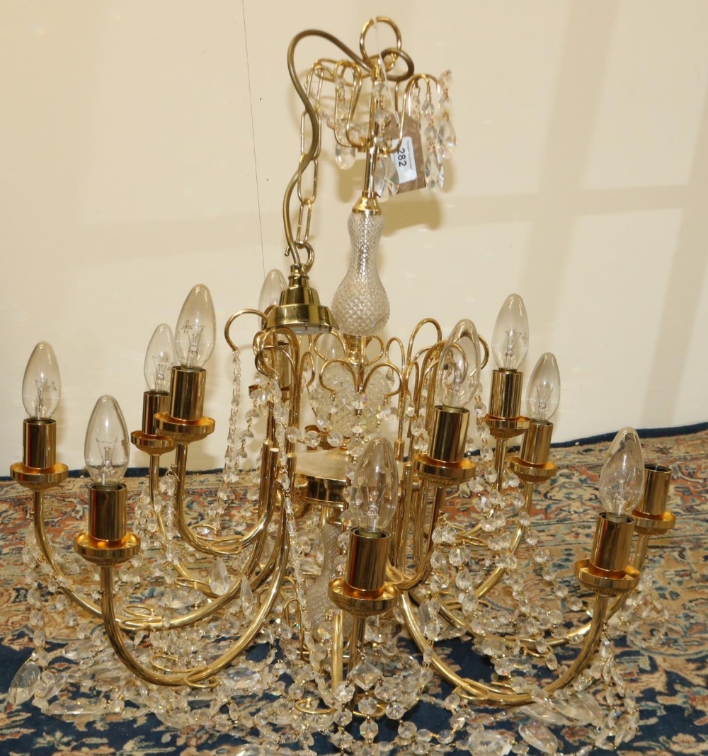 Gilt metal twelve branch chandelier, two tiers hung with prismatic swags, with etched shades