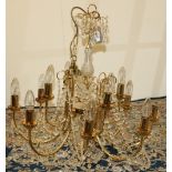Gilt metal twelve branch chandelier, two tiers hung with prismatic swags, with etched shades