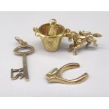 Four 9ct yellow gold charms including a 21st key, champagne in bucket, lucky wishbone and pony,