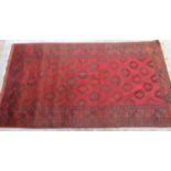 Caucasian red ground wool rug, field with geometric medallions, in repeating hooked stylized striped