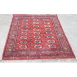 Turkoman Uzbek Bokhara rug, with 18 banked stylised guls on a rust red ground, border set with