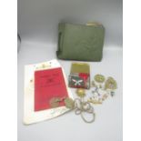 Tin containing various regimental cap badges and shoulder patches, WWII dog tags for 'Armitage