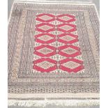 C20th Bokhara wool rug, central red ground field with lozenge motif surrounded by geometric