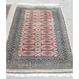 C20th Bokhara wool rug, salmon pink ground central field, set with 22 stylised medallions surrounded