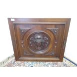 Walnut door panel, centered by a ribbon tied mask head in a moulded roundel with oak leaf carved