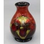 Moorcroft Pottery: Floral pattern flambe vase, tube lined with red and green flowers on red