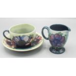 Moorcroft Pottery: Anemone pattern cup, saucer and jug, tube lined with red/purple flowers on