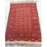 Bokhara red ground wool rug, field with octagonal medallions, in repeating hooked stylized striped