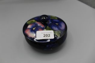 Moorcroft Pottery: Pansy pattern trinket pot and cover, tube lined with purple and pink flowers on a