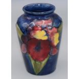 Moorcroft Pottery: Floral pattern baluster vase, tube lined with purple and yellow flowers on dark