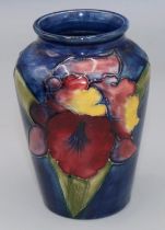 Moorcroft Pottery: Floral pattern baluster vase, tube lined with purple and yellow flowers on dark