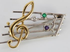 18ct yellow and white gold treble clef brooch, set with diamond, emerald and amethyst, stamped