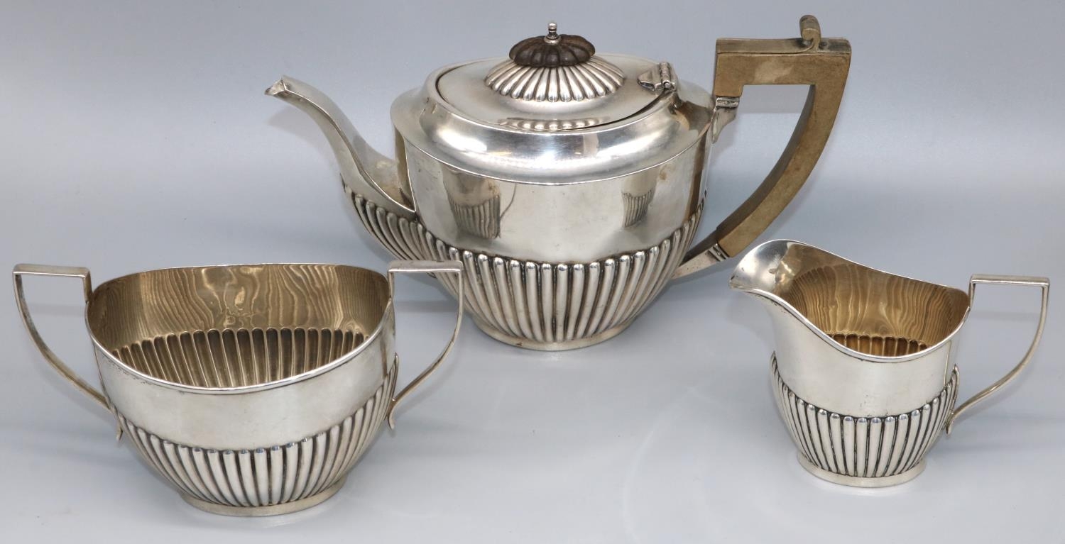 George V hallmarked silver three piece tea service, with part lobed oval bodies, teapot with