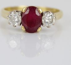 18ct yellow gold ruby and diamond ring, the central oval cut ruby flanked by two round cut diamonds,