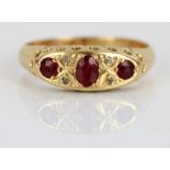 18ct yellow ruby and diamond ring, the three rubies and four diamonds in ornate rub-over setting, on