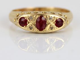 18ct yellow ruby and diamond ring, the three rubies and four diamonds in ornate rub-over setting, on